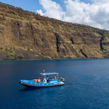 a small boat in a body of water with a mountain in the background