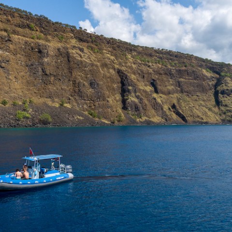 a small boat in a body of water with a mountain in the background