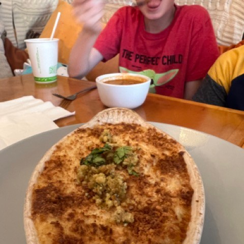 a young boy sitting at a table with a plate of pizza