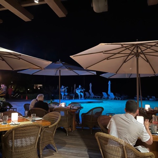 a group of people sitting at a table with a blue umbrella