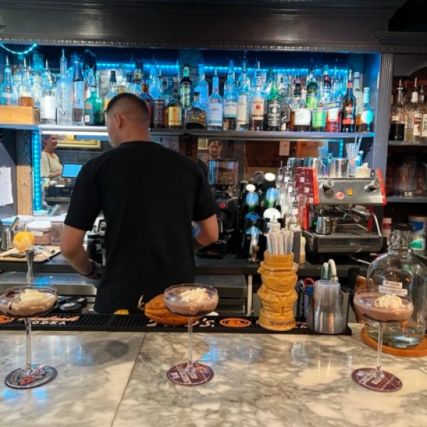 a bar with a bartender and 3 chocolate martinis on the bar