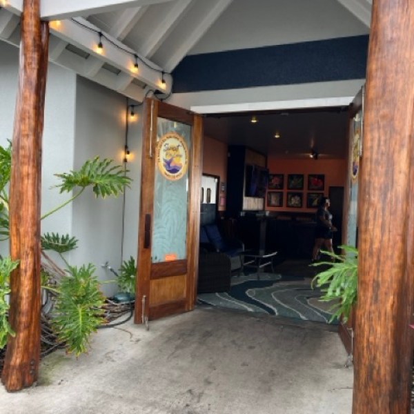 entrance to a restaurant called Sunset Kai Lani. With wooden tree poles on either side