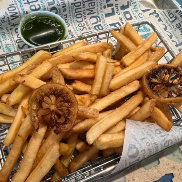a basket of lemon fires with a chimichurri sauce