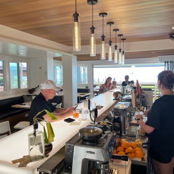 side view of a brightly lit bar with a man sitting and a bartender behind the bar