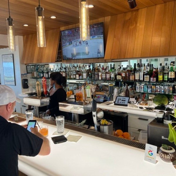 a brightly lit bar with a man sitting and a bartender behind