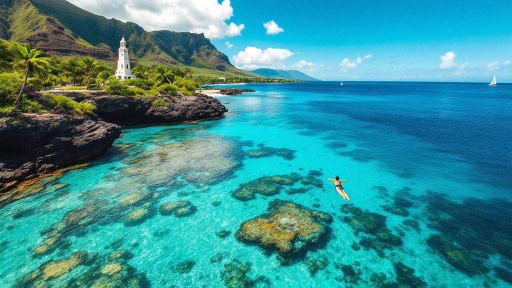 Person swimming in clear turquoise sea near a coastline with cliffs and lighthouse, distant sailboat visible.